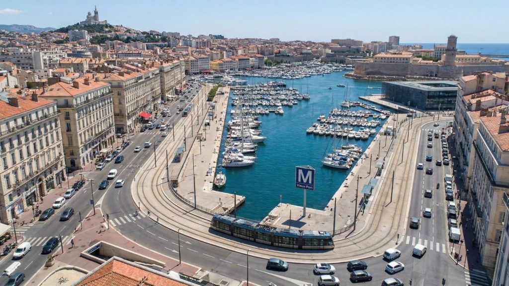 Vue aérienne ensoleillée du Vieux-Port de Marseille et de l'embouchure de la Canebière, illustrant l'emplacement stratégique et central pour domicilier une entreprise.